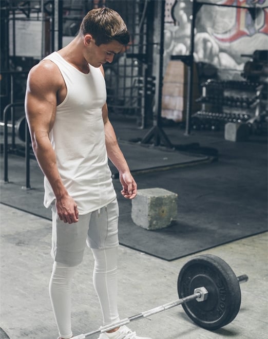 Fit man standing next to a barbell in the gym